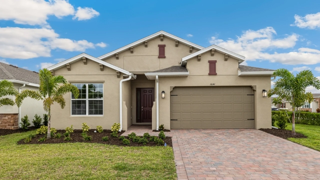 Outside of the Shelby L model. Cream home with two car garage, large window, and front door. Mixed paver driveway.